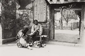 Daily life: Man having his toenails cut on street, China, c. 1910