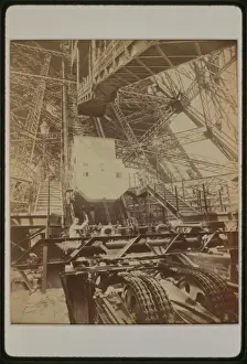 Tissandier Prints: Eiffel Tower machinery with man beside wheel that raises ele