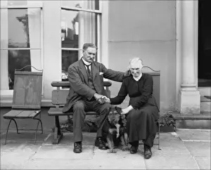 An elderly couple holding hands outside their house