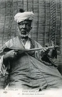 Elderly Moroccan man playing a sintir, also known as the guembri, gimbri or hejhouj Elderly Moroccan man playing a sintir, also known as the guembri, gimbri or hejhouj