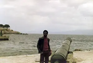 Errol Prints: Errol Holder standing beside the cannon on a Greek Island