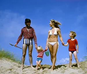 Family of four holding hands on a beach, West Country