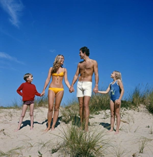 Family holding hands on sand dunes