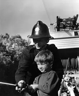 Images Dated 16th November 2016: Fireman showing boy how to use a hose