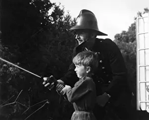 Fireman showing boy how to use a hose