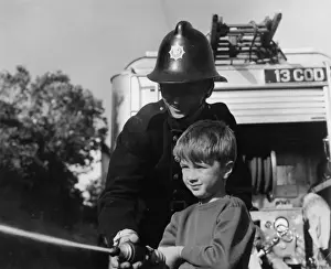 Fireman showing boy how to use a hose