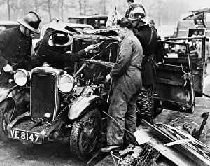 Examining Prints: Firemen and mechanic with burnt-out car, London