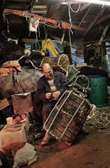 A fisherman mends a lobster pot in his waterside shed A fisherman mends a lobster pot in his waterside shed