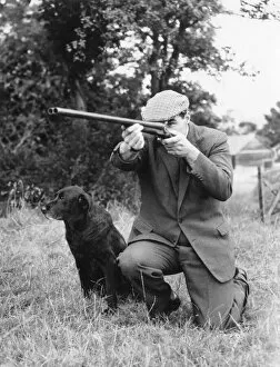 Tweed Gallery: Gamekeeper taking aim, his dog at his side