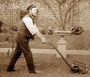 Gardener mowing a lawn with a Thomas Green lawnmower