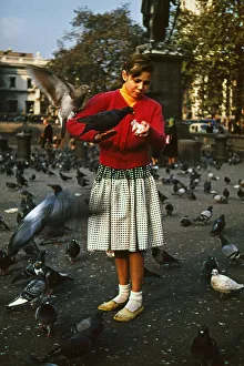 Girl feeding pigeons in Trafalgar Square, London