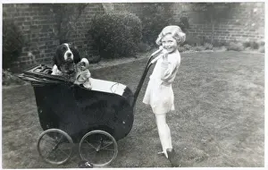 Girl in a garden with dog and doll in pram