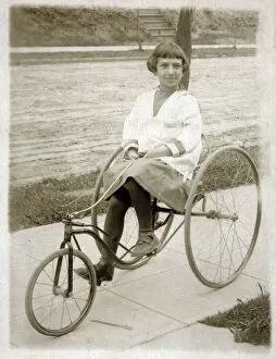 Wheeler Collection: Girl riding a vintage peddle tricycle along the sidewalk