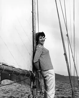 Girl in striped shirt leaning on the mast of a sailing boat