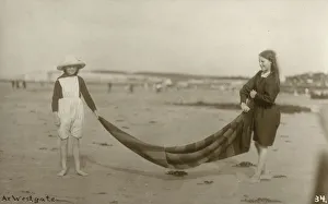 Two Girls folding up a striped blanket on the beach at Westgate-on-Sea in northeast Kent Two Girls folding up a striped blanket on the beach at Westgate-on-Sea in northeast Kent