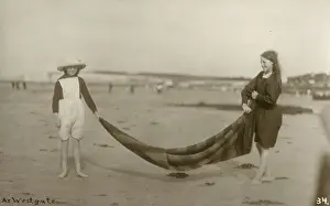 Two Girls folding up a striped blanket on the beach at Westgate-on-Sea in northeast Kent