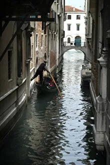 Venezia Gallery: Gondolier fends off boat from a wall with his foot, Venice