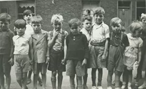 A group of children lined up for a photograph in a terraced street. Date: 1930s