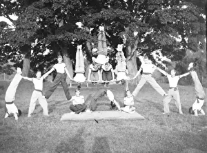 Acrobatics Prints: Group of servicemen doing acrobatics in a field