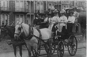 Horse drawn carriage full of ladies in big hats