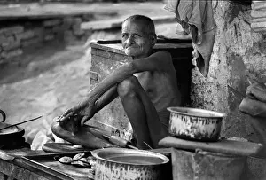 Nineties Prints: Indian man sits among his pots and pans, Old Delhi, India