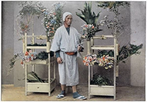 Images Dated 30th March 2021: A Japanese flower seller stands by a portable stall made of bamboo with integral holders