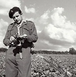 Pickering Prints: John standing in field in uniform carefully adjusting his camera