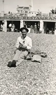 Holidaymaker Prints: Jolly British gent sitting on beach in front of a restaurant