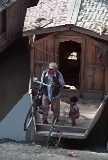 Jammu Prints: Kashmir, Dal Lake. A man lifts his bicycle off his boat