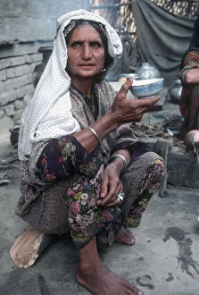 Squatting Collection: Kashmir - senior woman in traditional dress eats from bowl