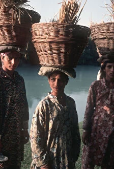 Images Dated 27th August 2019: Kashmiri women wearing Kashmiri shirts with baskets of reeds
