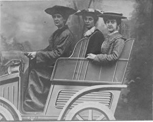 Three ladies posing for a studio photograph in a fake car. Date: c.1900