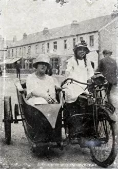 Two ladies on veteran motorcycle combination in street