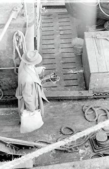Ropes Collection: Life on a North Sea trawler - aerial view onto the deck - man in raincoat and trilby hat