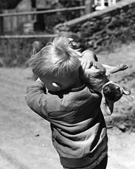 Surprised Gallery: Little boy carrying a dog over his shoulder