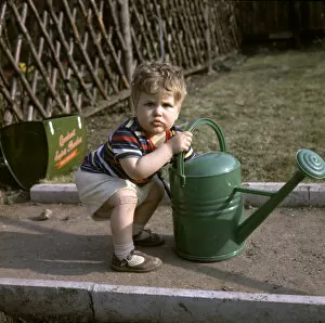 Images Dated 26th May 2017: Little boy with green watering can in a garden