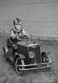 Steering Prints: Little boy sitting in a toy car