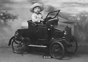Little boy in toy car in studio portrait