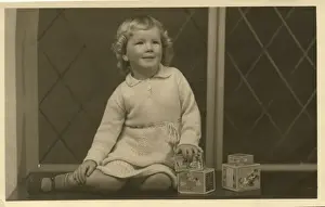 Jan21 Prints: A little girl grins for her photograph, alongside some toy building blocks