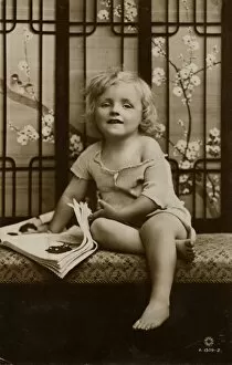Images Dated 16th December 2011: Little girl sitting on a bench with picture book