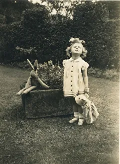 A little girl stands to attention and grimaces for the camera in a garden holding a doll A little girl stands to attention and grimaces for the camera in a garden holding a doll