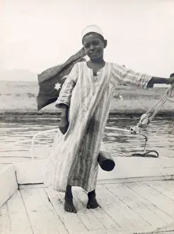 Steers Prints: The little son of a ferryman at Luxor, Egypt, steers his fathers boat with his leg