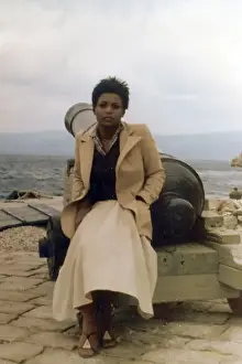 Lorna Prints: Lorna Holder, sits by a cannon on a Greek Island