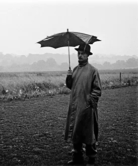 Images Dated 27th April 2021: Man with broken umbrella stands in pouring rain