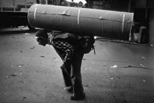 A man carrying a huge roll of heavy material on his back