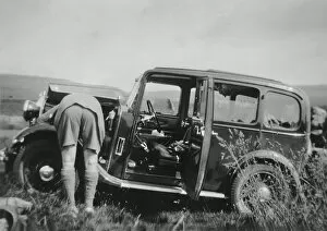 Man checking car engine in a field