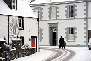 Cold Gallery: Man in a heavy overcoat walks a small child through the snow
