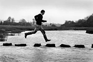 A man leaps along the stepping stones at Ogmore Castle