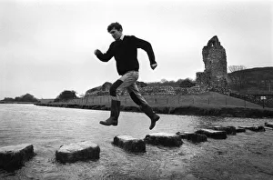 Images Dated 2nd July 2019: A man leaps along the stepping stones at Ogmore Castle