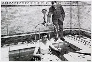 A man been lowered by crain into a bath of hundreds of gallon of radio-active water, for treatment for diseases such as tuberculosis, in Bath, Somerset